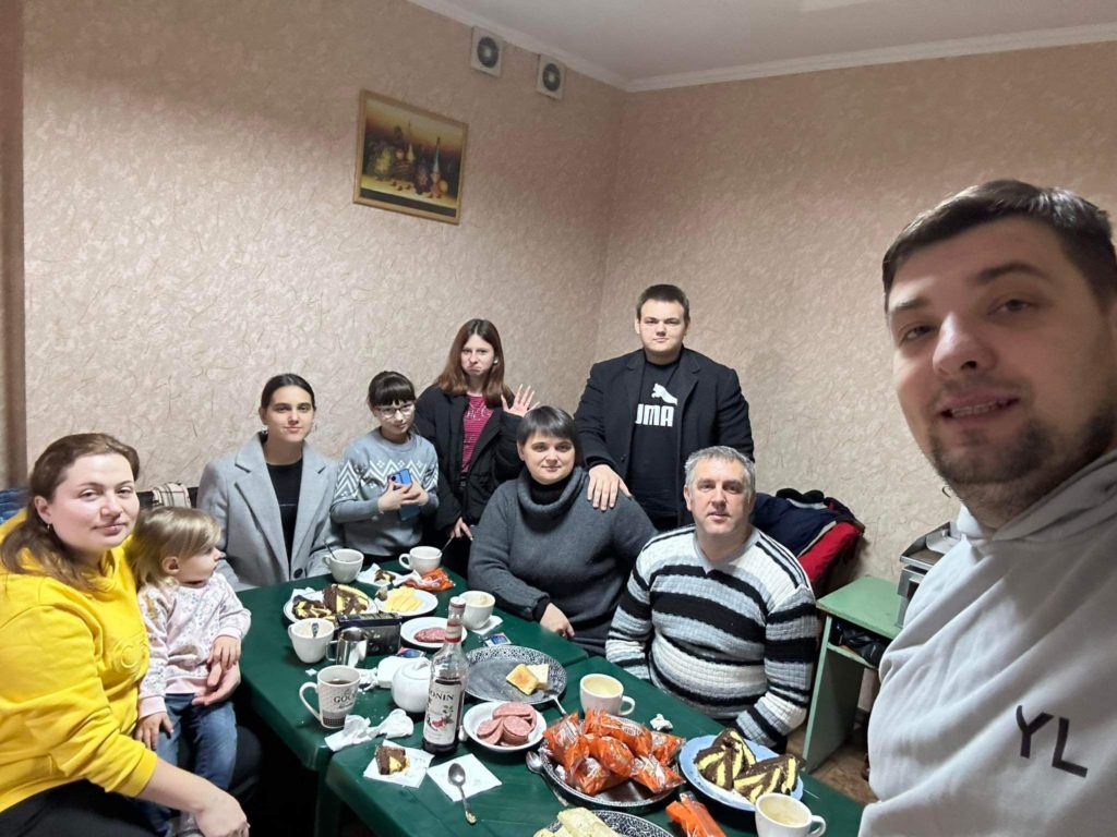 Bohdan with Pastor Andrew and their families sat around a table during a meal.