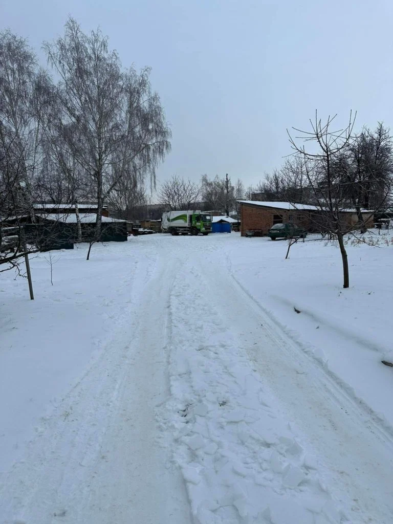 A snowy scene in Lebedyn with a snow covered road leading to buildings in the distance.