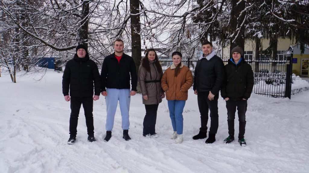 The team standing in a line in front of some trees in the snow outside the Centre