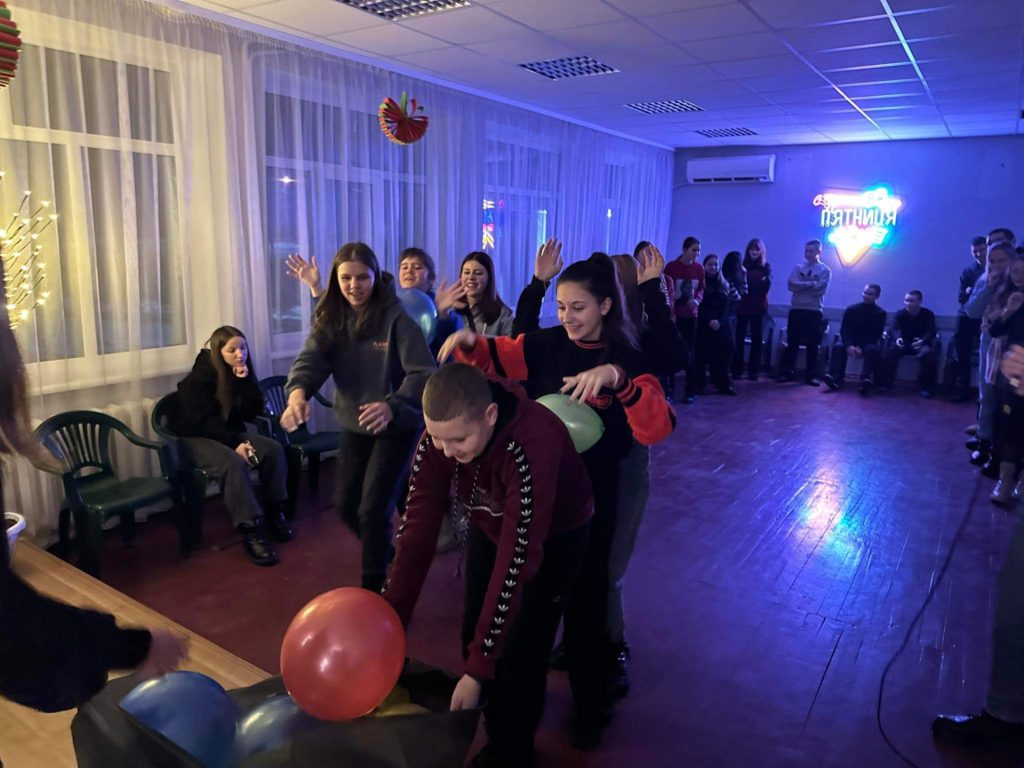 The youth group playing a game involving loading balloons into a black sack in the evening time at the Centre