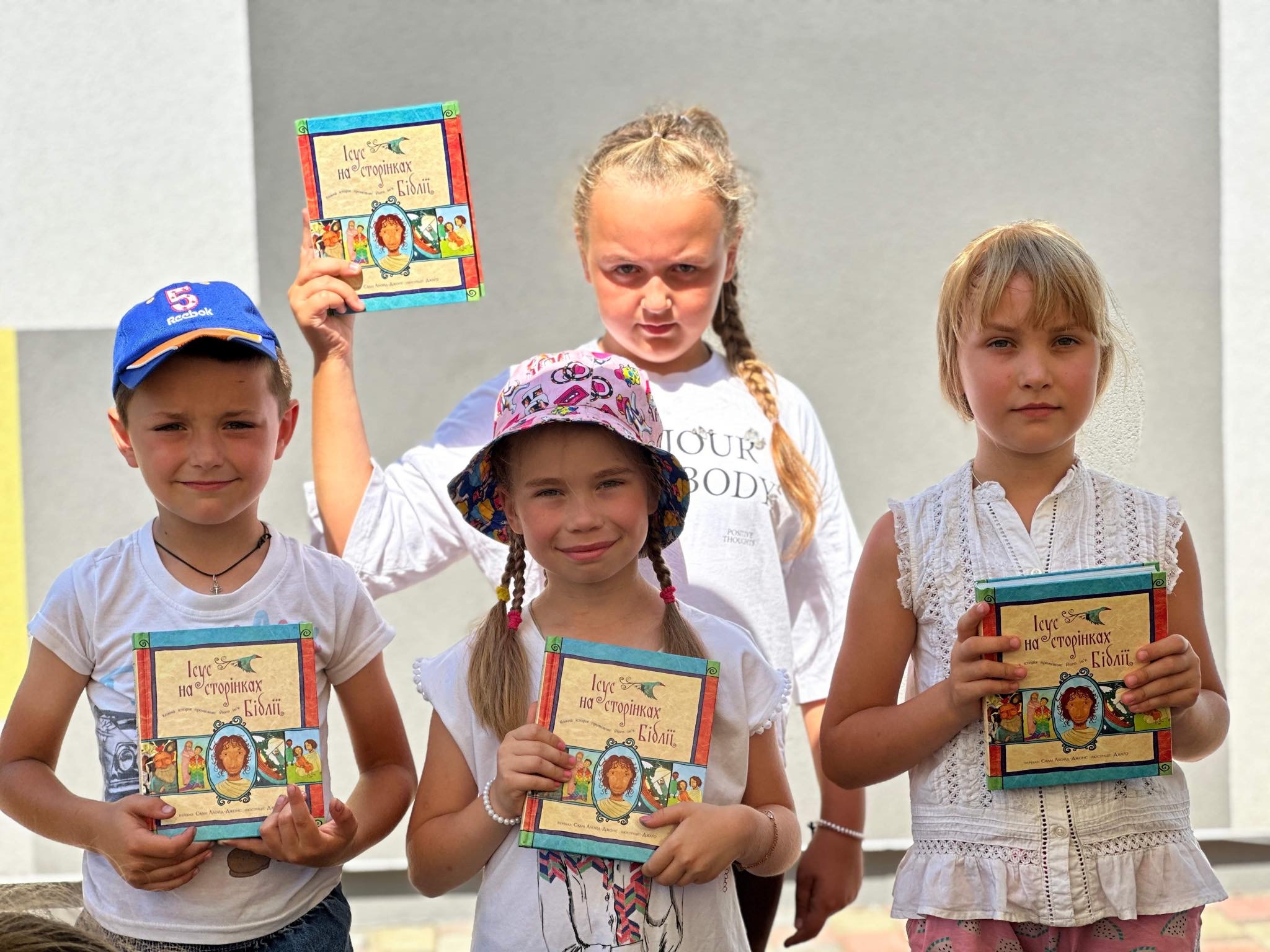 A group of four children holding their copies of the Jesus Storybook Bible that they have been given