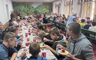Children eating together on long tables at Summer Camp 2024