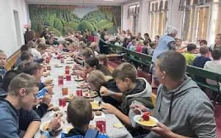 Children eating together on long tables at Summer Camp 2024