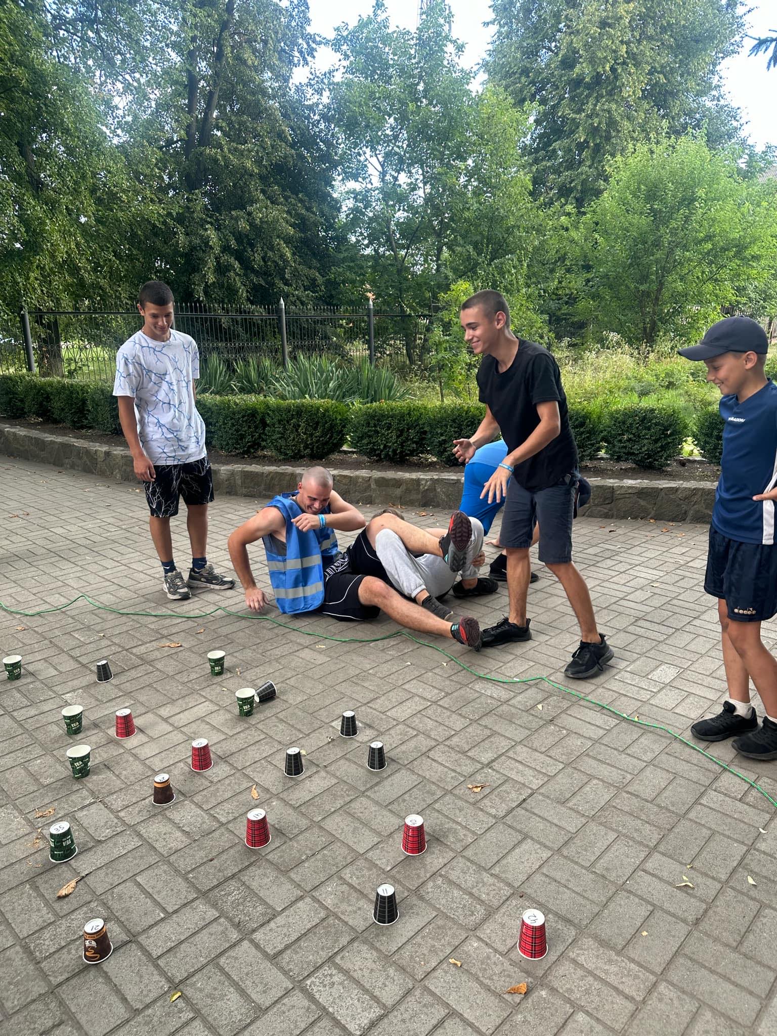 Teenage boys playing a game with upside down cups on the ground outside