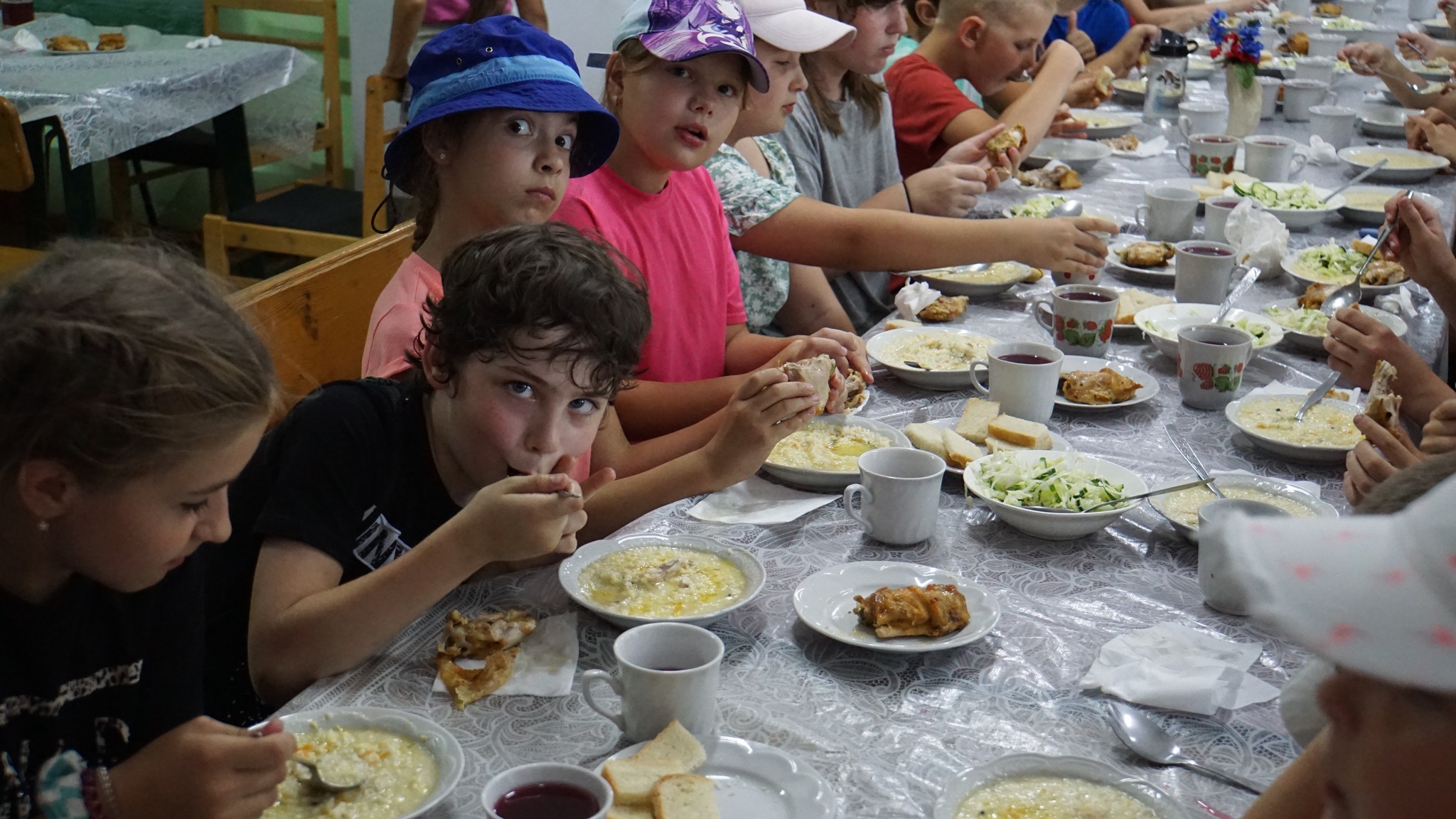 Children sitting at a long table in the Centre eating a meal