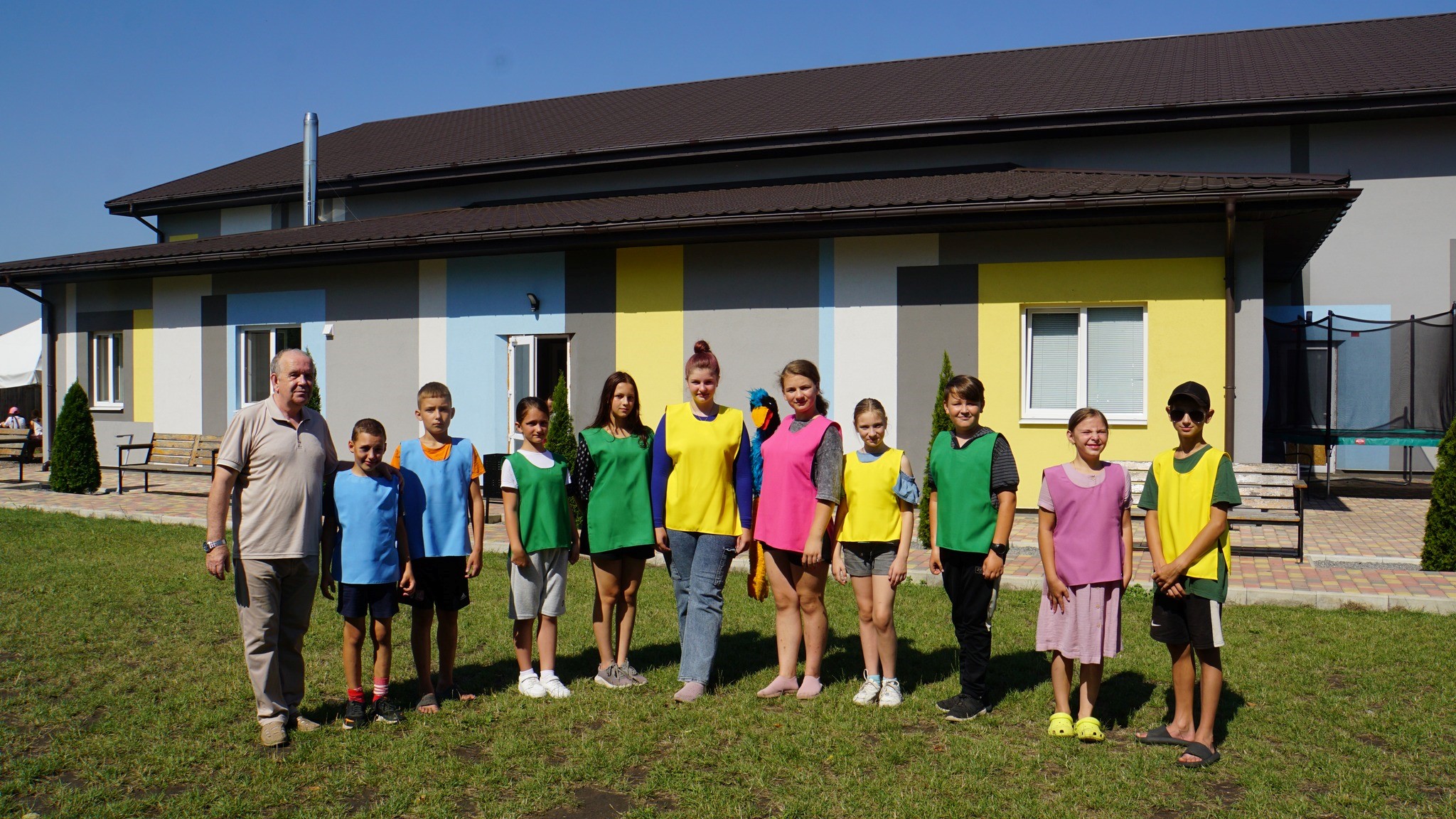 Children in coloured sports bibs standing in a line facing the camera