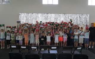 Summer Camp Week 2 children posing together for a phot with their arms waving in the air