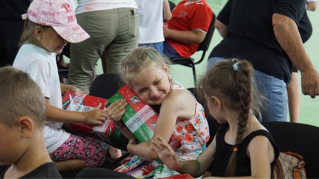 A little girl hugging the present she has been given with a big smile on her face