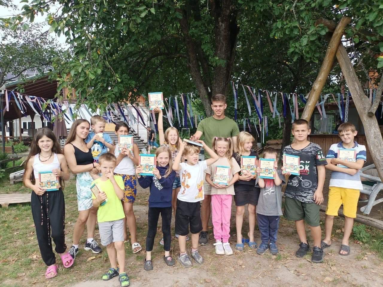 13 of the children at the camp in Zhytomyr standing in a group holding up their copies of The Jesus Storybook Bible