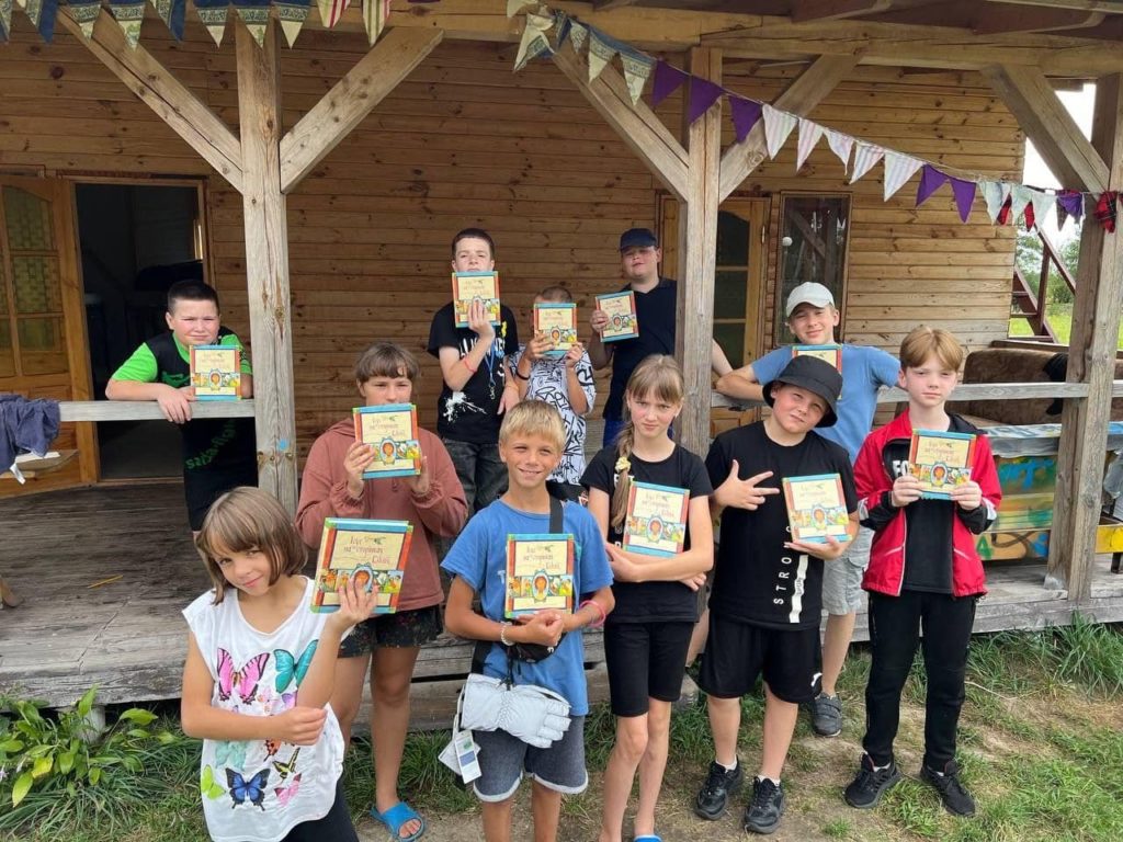 11 of the children at the camp in Zhytomyr standing in a group holding up their copies of The Jesus Storybook Bible