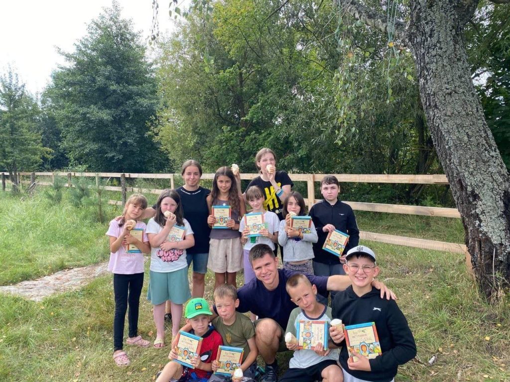 10 of the children at the camp in Zhytomyr standing in a group holding up their copies of The Jesus Storybook Bible