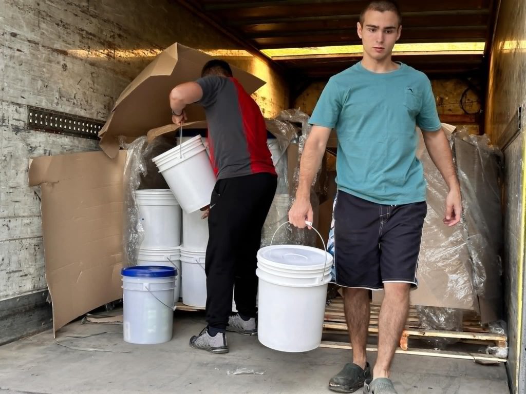 Men unloading buckets of food aid from a truck