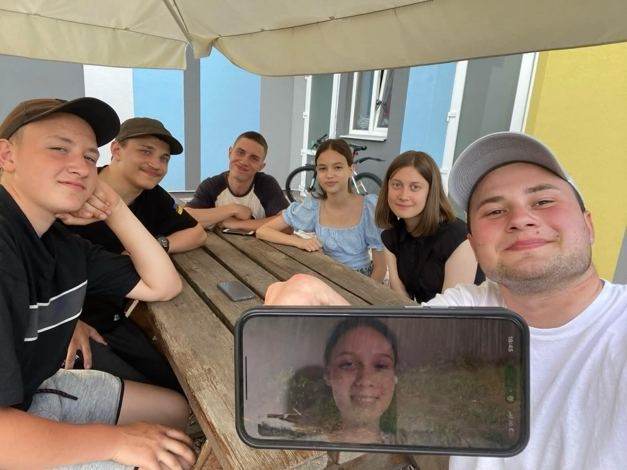 Valentin taking a selfie with a group of teenagers who want to be baptised, with one on a phone screen at the front of the picture.