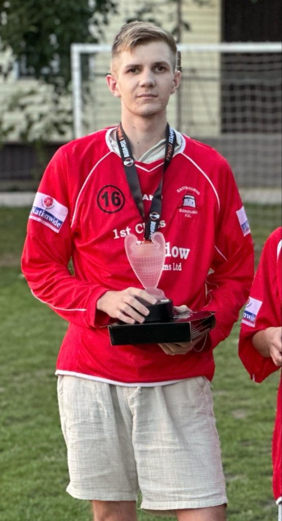 A photo of a boy called Ivan dressed in a red football shirt and holding a trophy