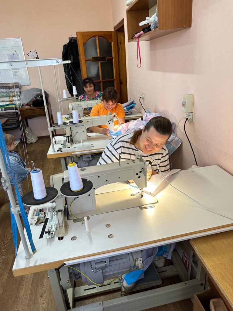 A lady sat at a sewing machine making bedding