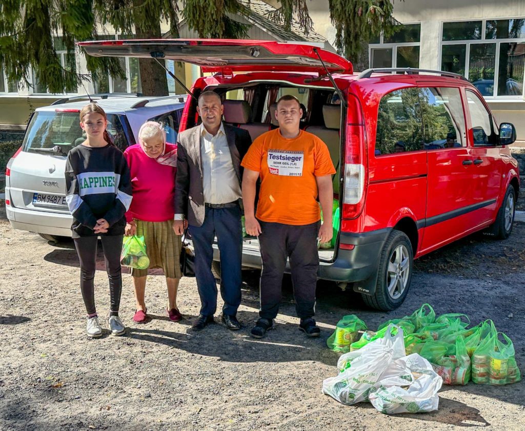 Pastor Andrew and his friends from Samotoivka standing in front of a van that has its boot open