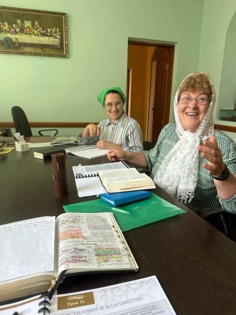 A photo of Vera who has become a Christian recently, and another lady sat at a table laughing at the camera