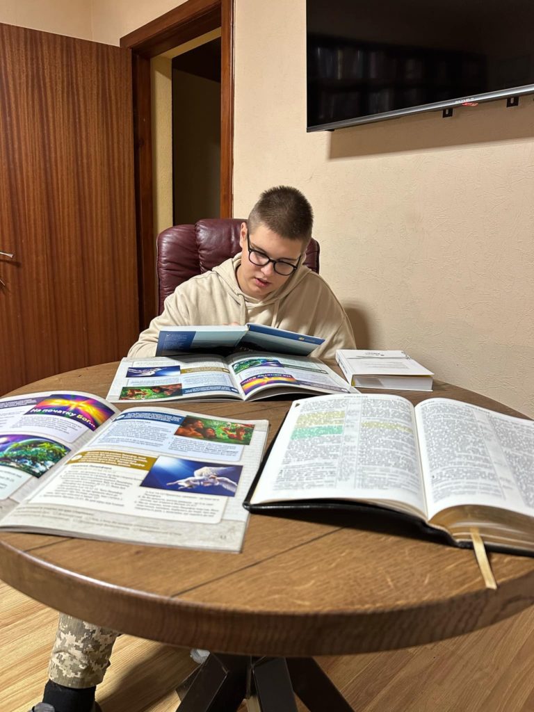 Egor sat at a table with his Bible and other books spread in front of him whilst he studies