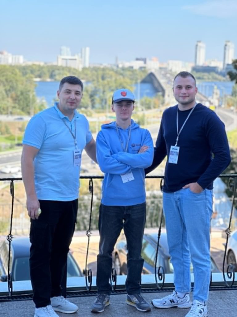 Farmer Sergey, Valentine and Bohdan posing for a photo in front of some railings at Kiev Theological Seminary