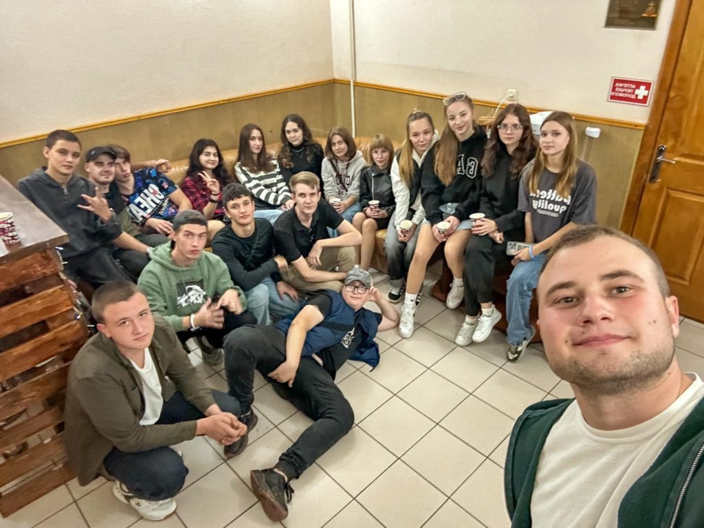 The youth from Valentine's homegroup sat on the floor and bench in a room at the Centre posing for a photo