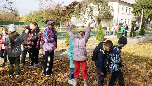 Girl throwing autumn leaves up in the air whilst playing outside with others at the Centre