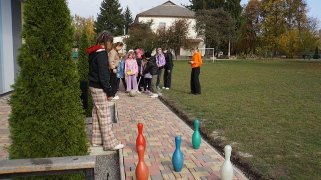 Children playing a game of giant skittles on a pathway outside the Centre