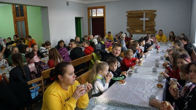 Children sat at two long tables in the Centre eating a meal together