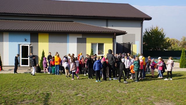 A large group of young children standing around outside the Centre in the sunshine