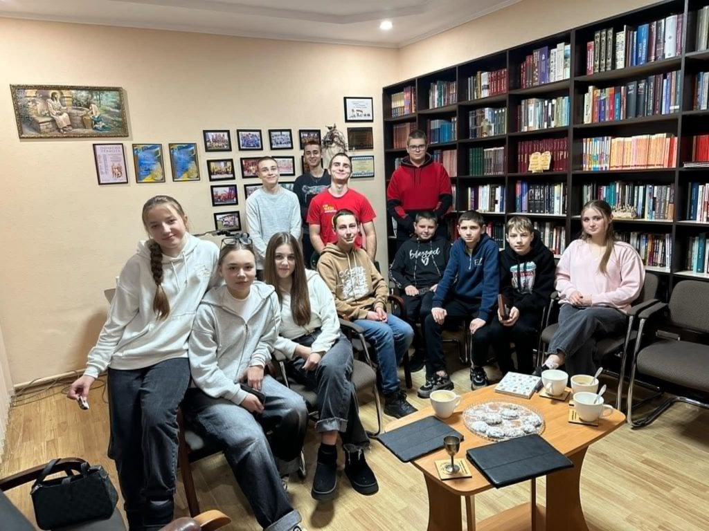 A group of 12 of the youth standing and sitting posing for a photo whilst gathered to pray for their friends in Sumy city