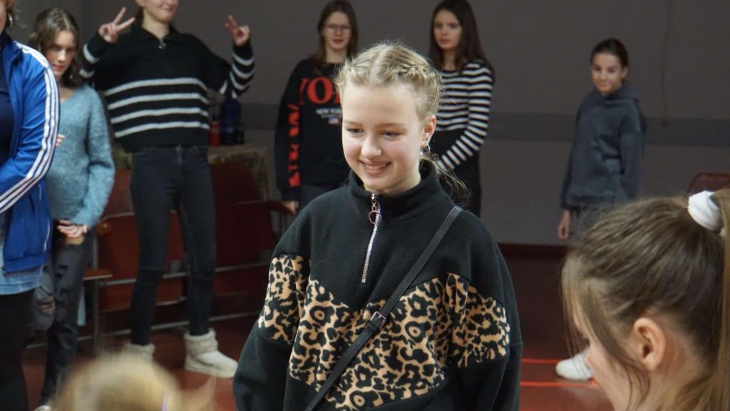 One of the young girls standing smiling in a room at the Cntre