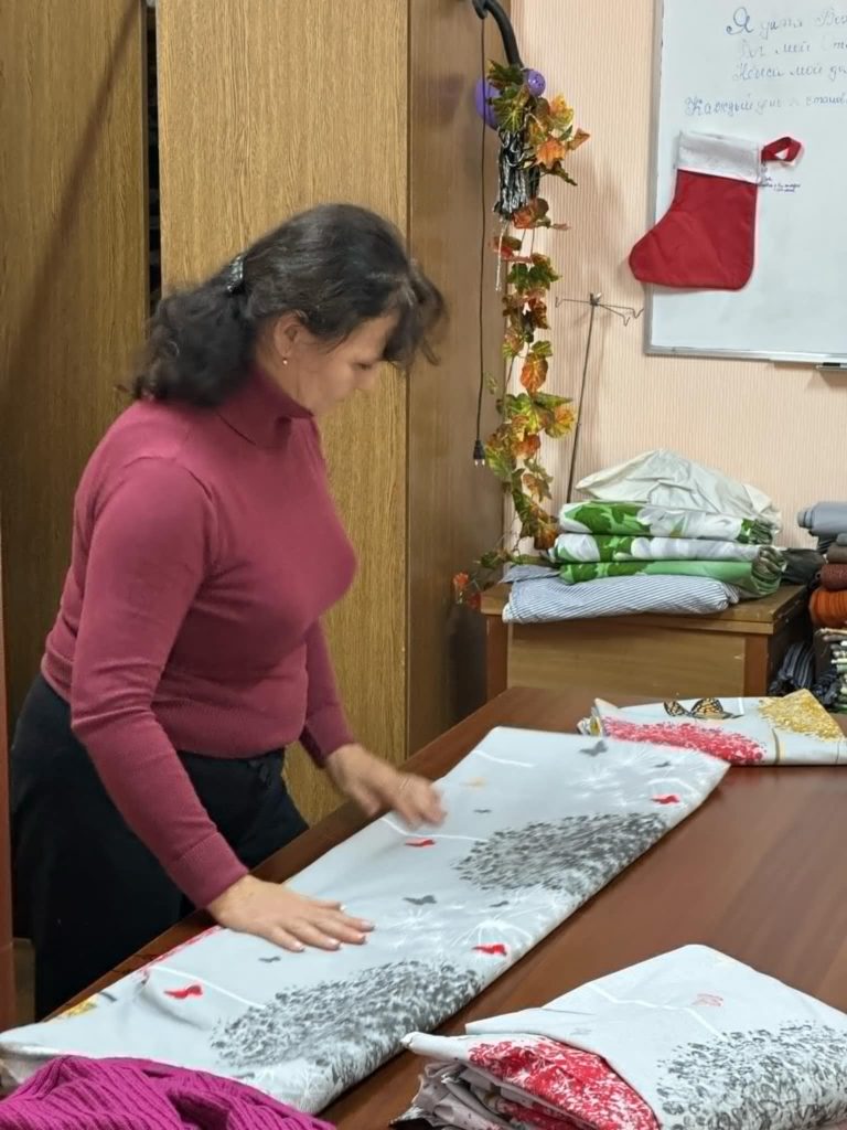 A lady folding a bedding sheet on a table