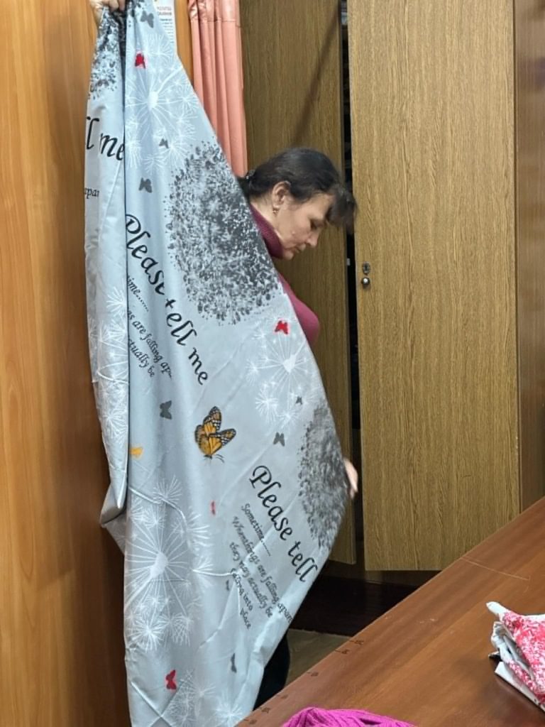 A lady folding two ends of a bedding sheet together