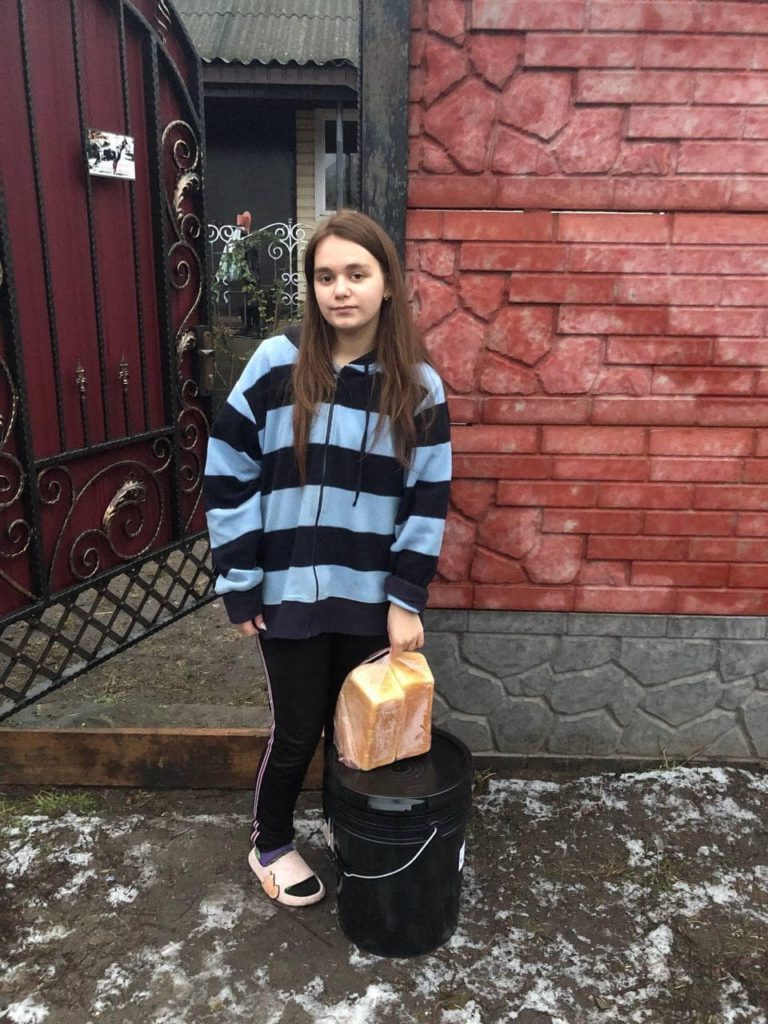 a young girl standing outside in her slippers with donated aid