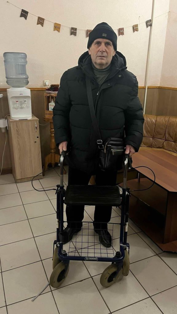 One of the refugees standing with a walking frame on wheels