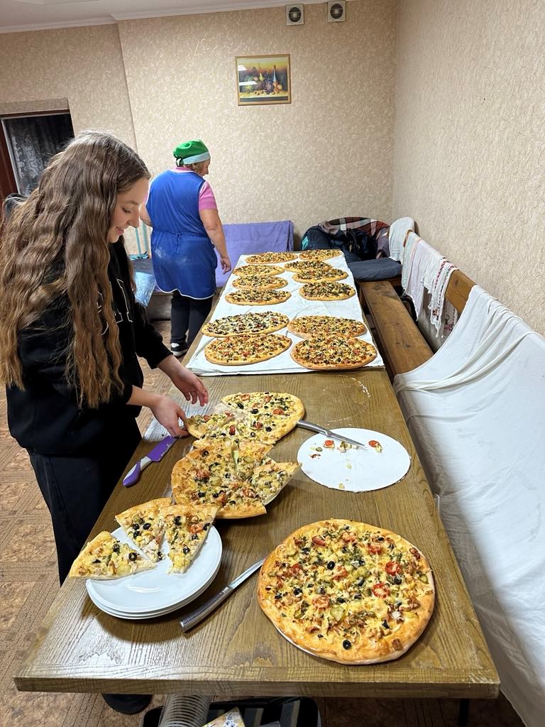 Tables of pizza laid out with one of the youth group taking a slice