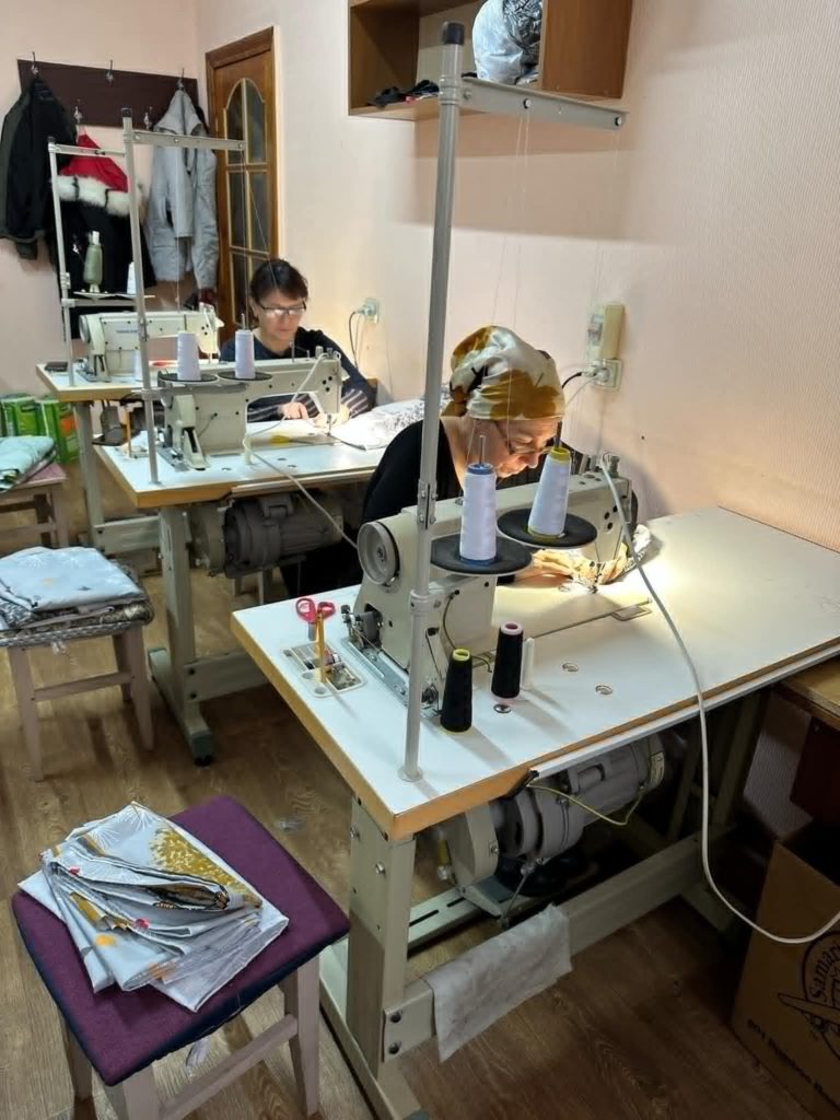 Two ladies sat at sewing machines making bedding