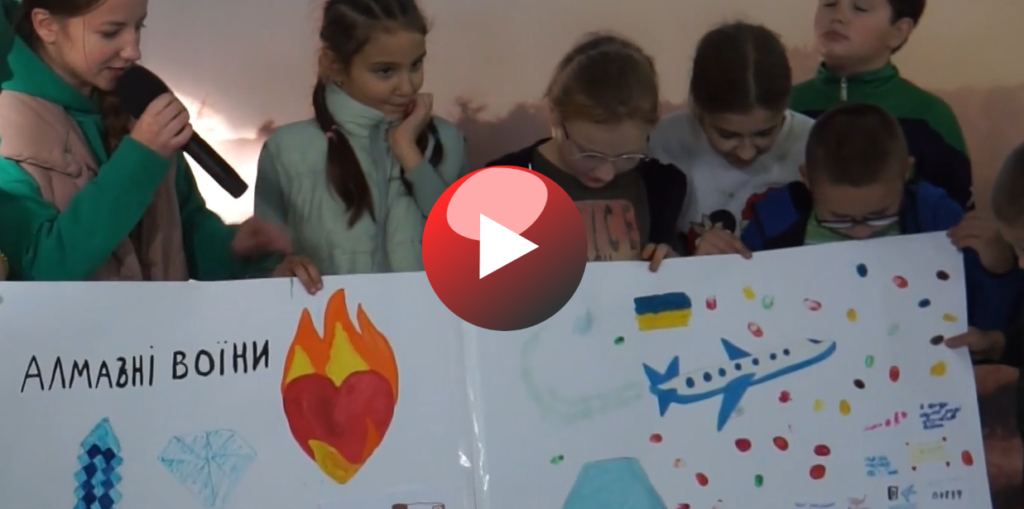 Video still image show children holding a banner