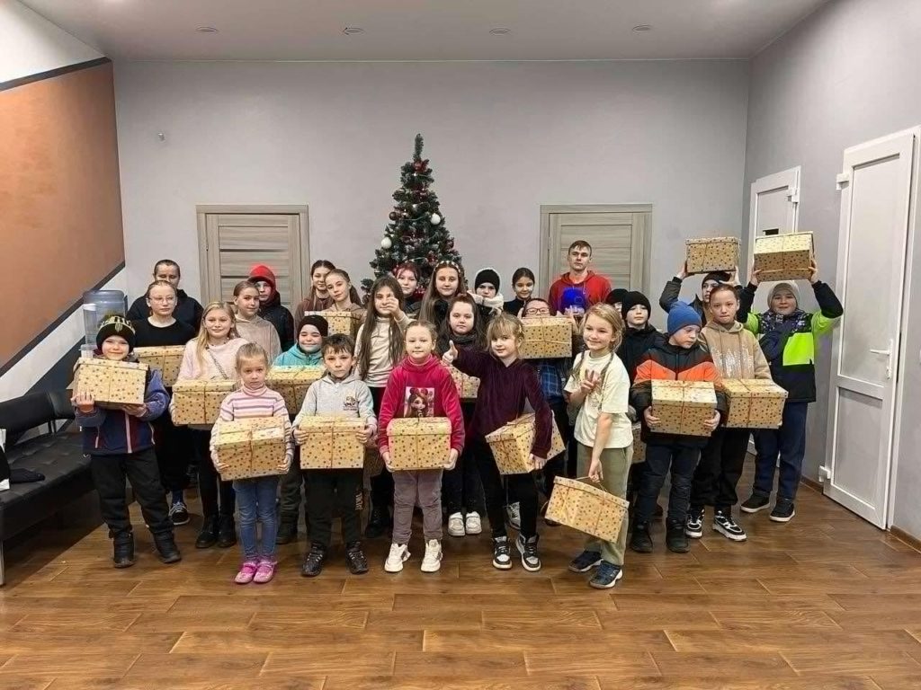 28 of the children standing in a room at the Centre holding Christmas presents they have been given