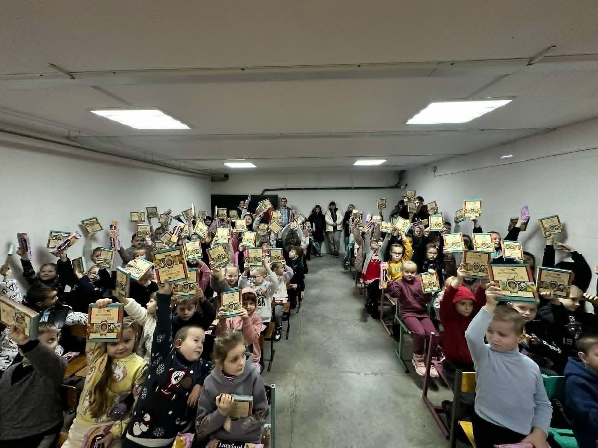 Rows of children sat inside the bomb shelter at the school in Mykolaivka holding up their new copies of the Jesus Storybook Bible