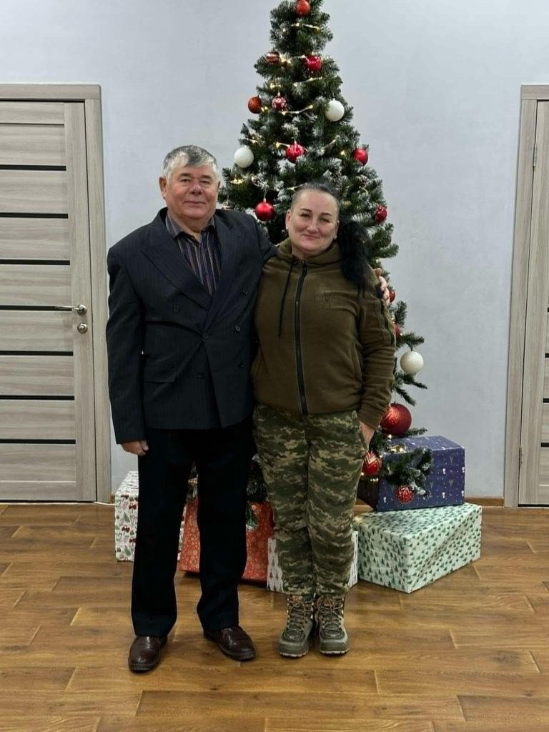 Pastor Sergey standing inside the Centre with his arm around Leila