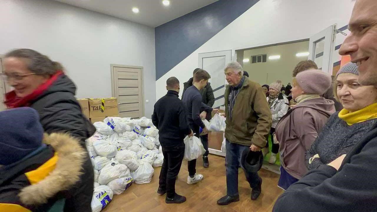 A large pile of aid in white bags standing on the floor that is being given to people as they come through a door at the Centre