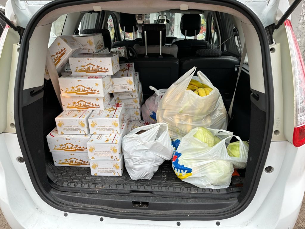 A car boot filled with present boxes and bags of fruit and vegetables