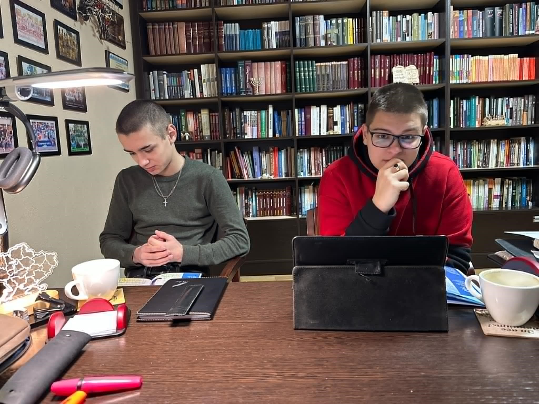 Igor and Sasha sat across the desk studying with books and a tablet