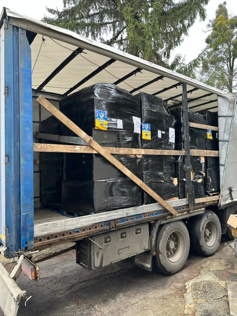 Pallets of aid wrapped in black plastic on a curtain sided truck waiting to be unloaded