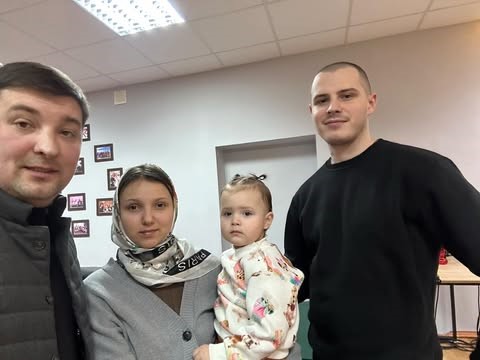 Bohdan taking a selfie with a lady holding a baby and her husband