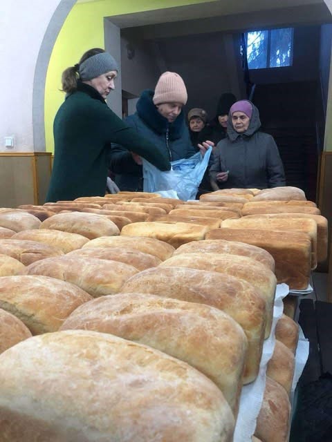 a closeup of tales of loaves of bread with people collecting them in the background