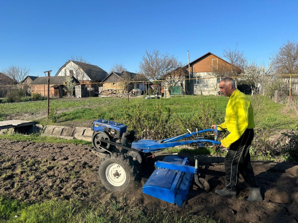 A man planting seed potatoes in a field using a machine