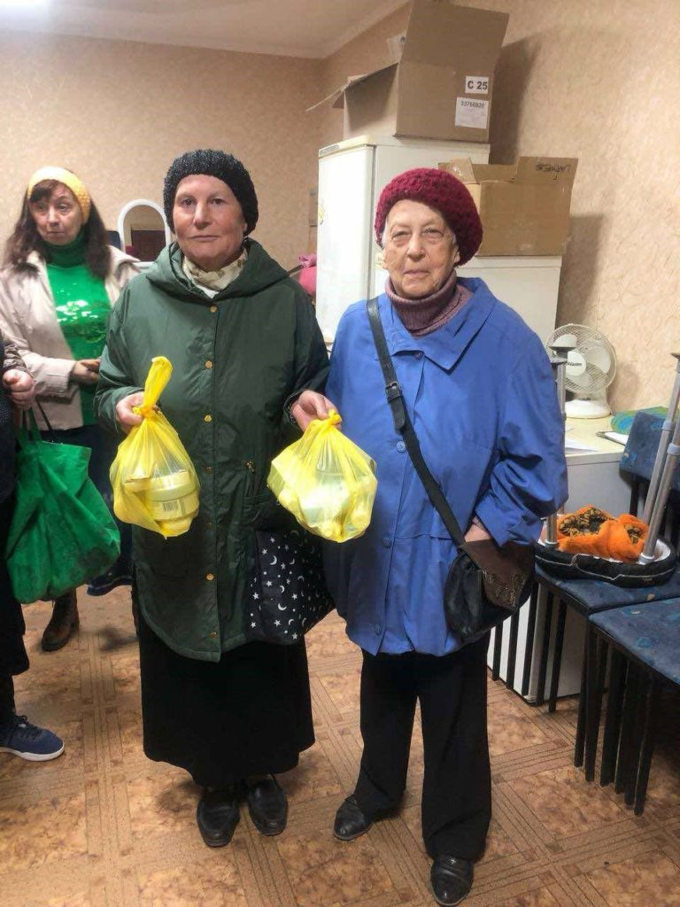 Twp ladies stood indoors holding bags of aid
