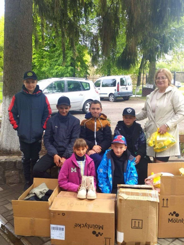 Children from an orphanage stood and sat behind boxes of donated aid