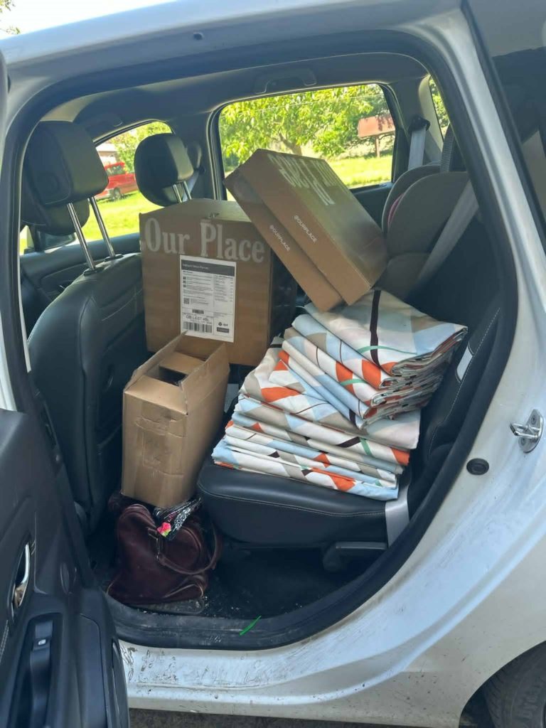 The back seat of a car loaded with bedding and boxes of supplies